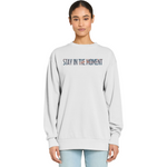 Person wearing a light gray sweatshirt with 'Stay in the Moment' text on a white background