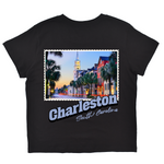 Black t-shirt with a colorful graphic of Charleston, South Carolina, featuring palm trees and buildings.
