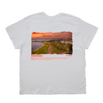 White t-shirt with a scenic print of Charleston, featuring a sunset over water and a path.