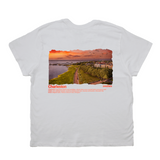 White t-shirt with a scenic print of Charleston, featuring a sunset over water and a path.