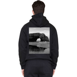 Person wearing a black hoodie with a scenic print on the back
