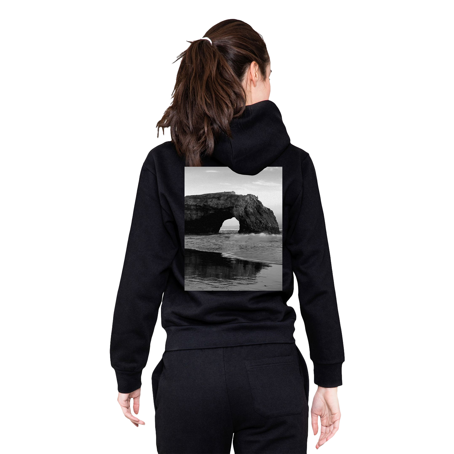 Person wearing a black hoodie with a scenic print on the back, standing against a white background