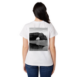 Person wearing a white t-shirt with a black and white photo of a natural arch on the back