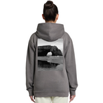 Person wearing a gray hoodie with a scenic print on the back, standing against a white background