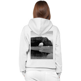 White hoodie with a black and white image of a natural arch on the back, worn by a person.
