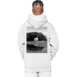 Person wearing a white hoodie with a scenic print on the back, standing against a white background